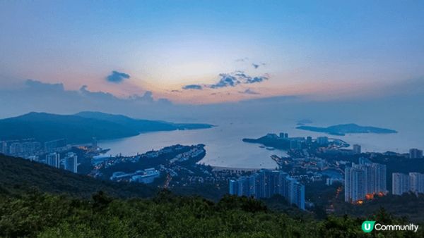 暮色蒼茫，群山環抱寧靜海灣，高樓林立，萬家燈火初上，海天一色...