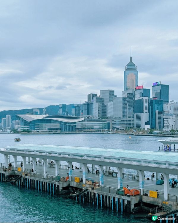 中環碼頭係打卡熱點，因為呢度有壯觀嘅維港美景，背後係高樓大廈...