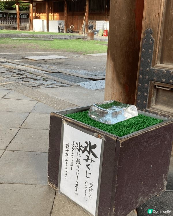 相片係日本神社門口，木箱上面擺咗大大舊冰，下面有張日文紙寫住...
