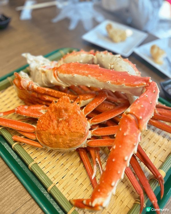 巨大的紅色帝王蟹，整隻蟹被完整地擺放在竹編托盤上。蟹殼呈現鮮...