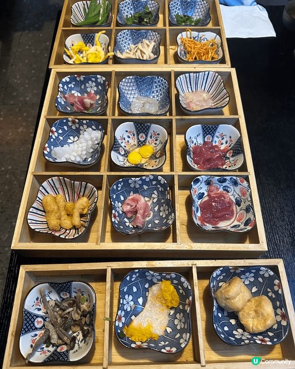 這張圖片展示了一個精美的木盤，上面放滿了各種日式小碟，有蔬菜...