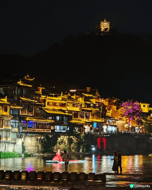 夜遊湖南鳳凰古城，河邊有大量穿著苗族傳統服飾的遊客以兩岸的舊...