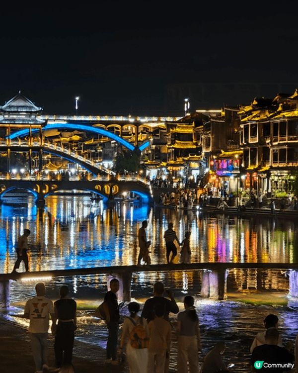 夜遊湖南鳳凰古城，河邊有大量穿著苗族傳統服飾的遊客以兩岸的舊...