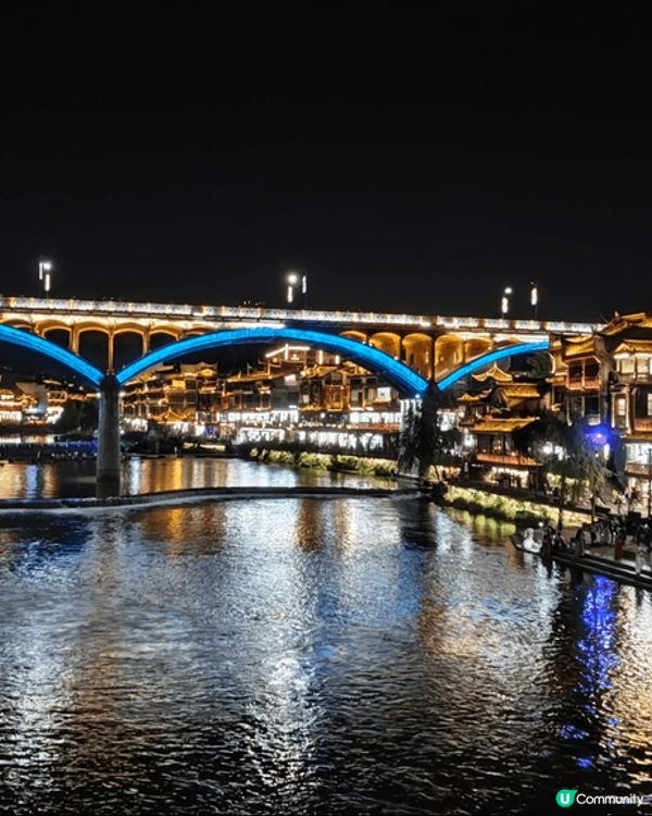 夜遊湖南鳳凰古城，河邊有大量穿著苗族傳統服飾的遊客以兩岸的舊...