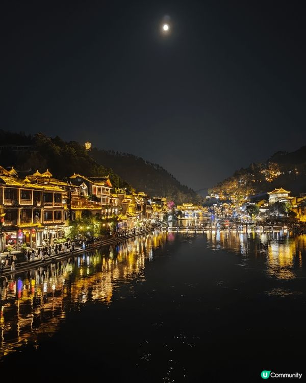 夜遊湖南鳳凰古城，河邊有大量穿著苗族傳統服飾的遊客以兩岸的舊...