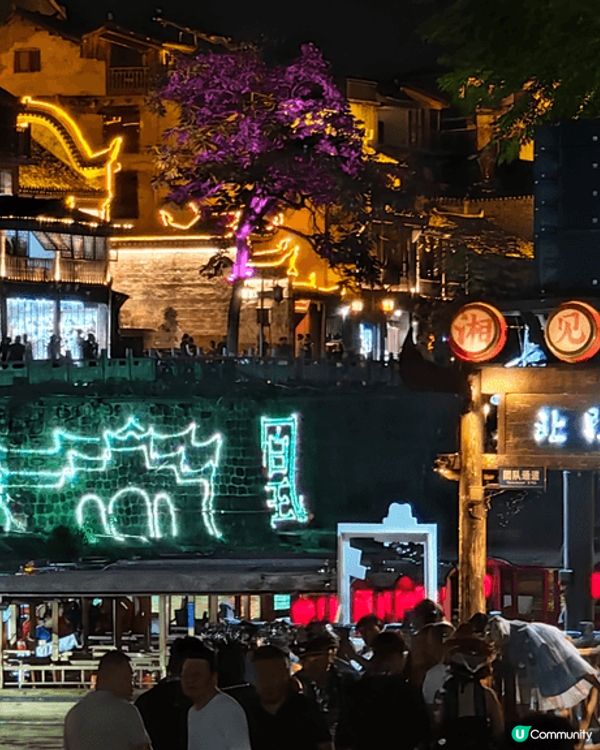 夜遊湖南鳳凰古城，河邊有大量穿著苗族傳統服飾的遊客以兩岸的舊...