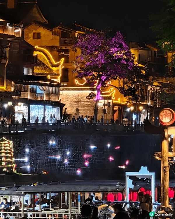 夜遊湖南鳳凰古城，河邊有大量穿著苗族傳統服飾的遊客以兩岸的舊...