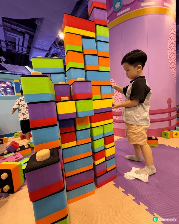 專注地堆疊彩色的大型積木，積木呈現紅、黃、藍、綠、紫等多種顏...