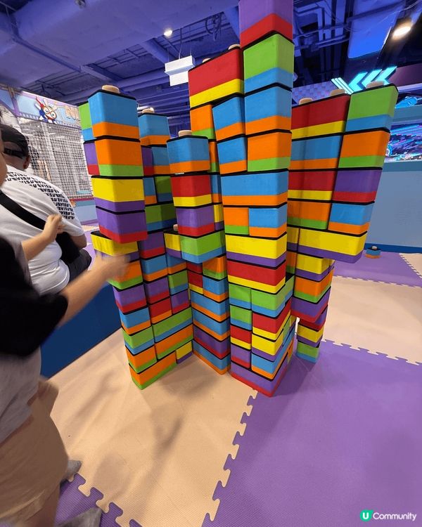 專注地堆疊彩色的大型積木，積木呈現紅、黃、藍、綠、紫等多種顏...