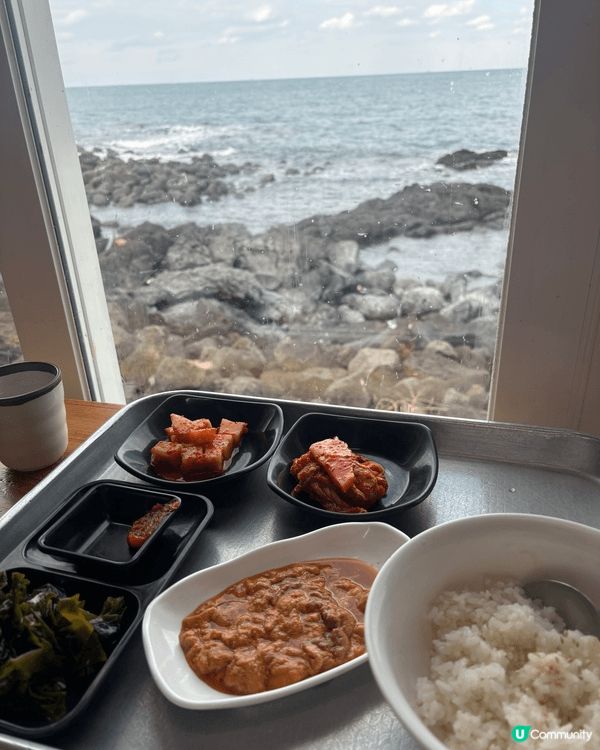 這是一碗豐盛的海鮮湯，裝在一個復古金屬鍋中，背景是海景。 湯...