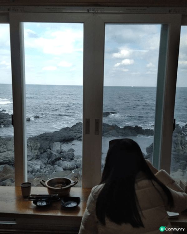 這是一碗豐盛的海鮮湯，裝在一個復古金屬鍋中，背景是海景。 湯...