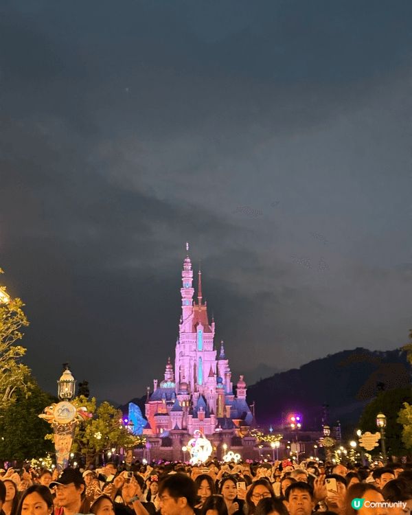 呢張照片係聖誕節期間嘅迪士尼夜景，燈飾閃爍，充滿節日氣氛。夜...