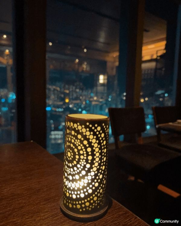 落地玻璃旁的燭光晚餐氛圍浪漫，牛扒香氣四溢，映襯城市夜景，光...