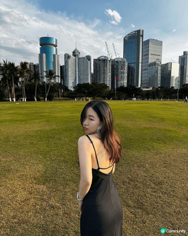 於三亞的廣闊草坪上拍攝的，背後是三亞現代化的城市天際線，高樓...