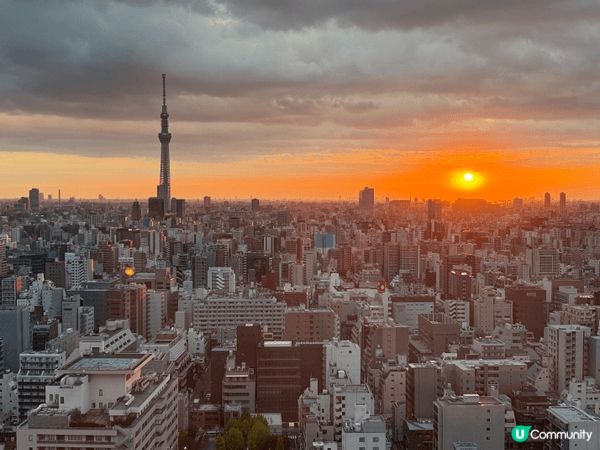 東京晴空塔喺夕陽下閃閃發亮，金色光輝鋪滿天空，塔影映照河面，...