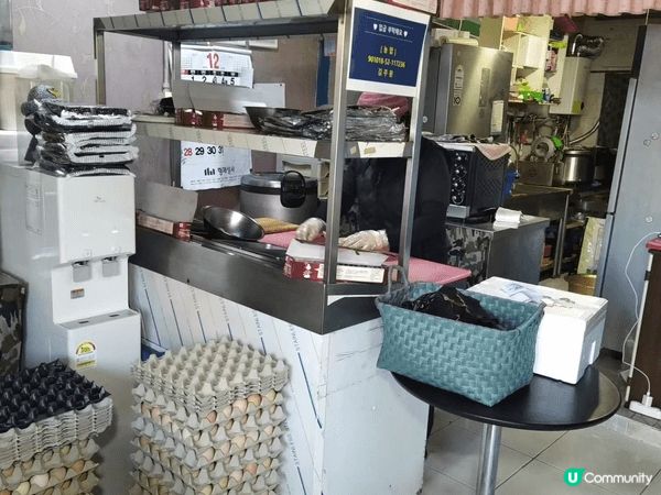 濟州島小店面內的小吃攤位，背景貨架上堆放著許多印有韓文「바이...