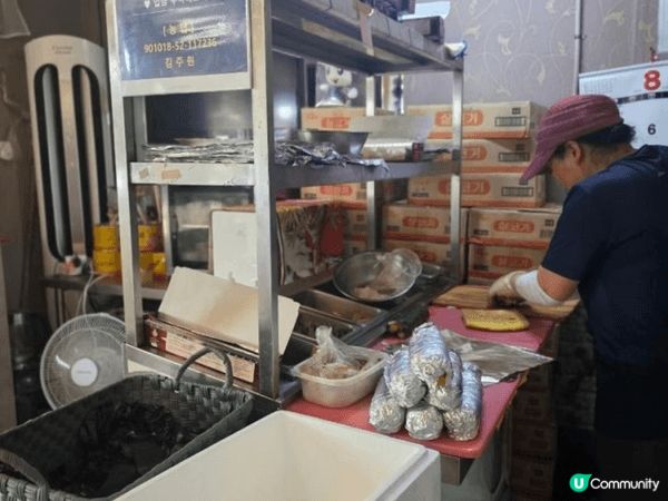 濟州島小店面內的小吃攤位，背景貨架上堆放著許多印有韓文「바이...